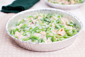 Two aluminum pie plates full of diabetic green bean casseroles sit on a picnic table.