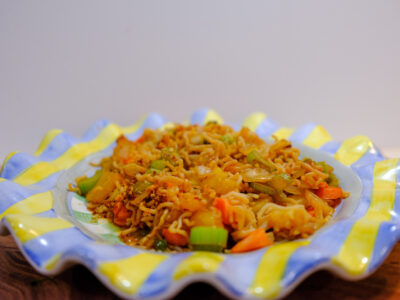 Sweet and spicy Thai fried rice, made low-carb and low-calorie with It’s Skinny rice and vegetables, served on a wavy blue and yellow striped dinner plate.